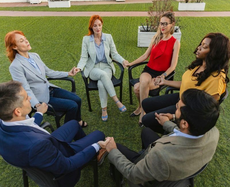 generational, multiracial business people sitting in circle having group discussion, group therapy